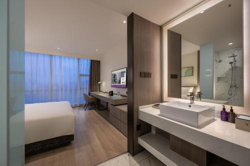 a bathroom with a bed and a sink and a mirror at Mercure Shanghai Hongqiao South in Shanghai