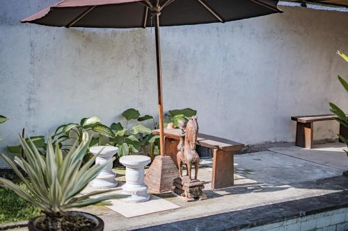 a table with an umbrella and a bench with a statue at Villa La Luna 2BR Joglo Style with Pool by Damaresa in Dalung