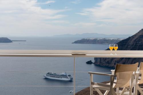 a balcony with a cruise ship and a glass of wine at Aria Suites & Villas in Fira