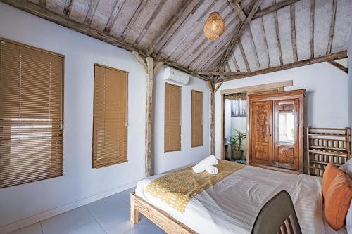 a bedroom with a large bed in a room with windows at Villa La Luna 2BR Joglo Style with Pool by Damaresa in Dalung
