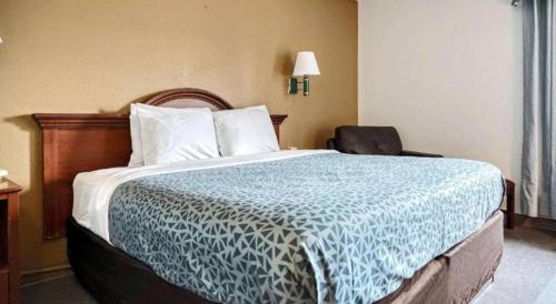 a bedroom with a large bed with a blue and white comforter at Econo Lodge Raleigh near Walnut Creek Amphitheatre in Raleigh