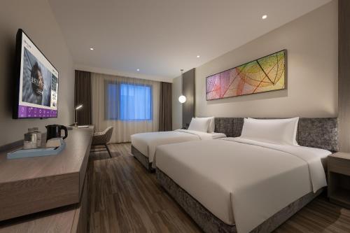 a hotel room with two beds and a desk at Mercure Shanghai Hongqiao South in Shanghai
