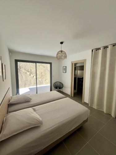 a bedroom with two beds and a large window at Villa de Luxe avec Piscine à débordement chauffée à Porticcio in Porticcio