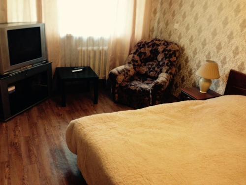 ペルミにあるApartment Kim 83のベッド、椅子、テレビが備わるホテルルームです。