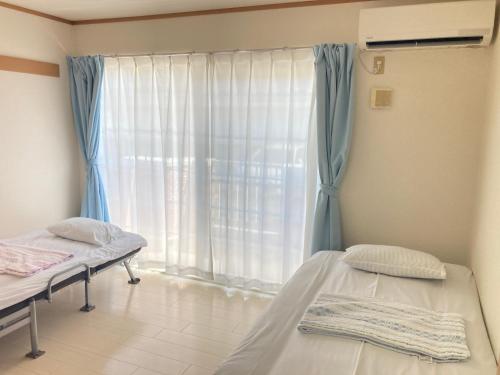 two beds in a room with a window at メゾンド寺田 アパート1室貸切 素泊まり最大6人宿泊可能 4名様まで同一料金 in Yamaguchi
