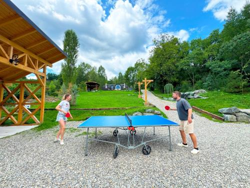 a man and a woman standing next to a ping pong table at Friday Inn Igloo - Intimitate, Jacuzzi, Natura, Priveliste & Iaz - Escapadă romantică premium la o oră de Bucuresti - Eco Friendly Micro-Resort in Comarnic