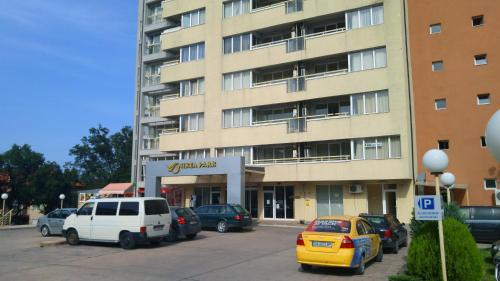 ein großes Gebäude mit auf einem Parkplatz abgestellten Autos in der Unterkunft Europroperties Nikea Park in Goldstrand