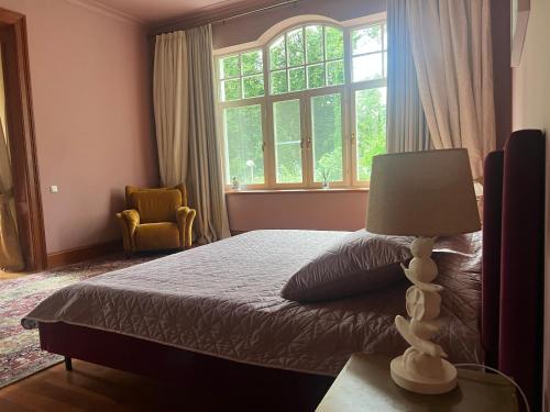 Un dormitorio con una cama con una lámpara y una ventana. en Villa Lumiere, en Jūrmala