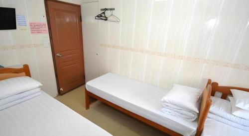 a small room with two beds and a door at New Mong Kok Guest House in Hong Kong