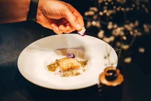 a person holding a white plate with food on it at Hotel Birkenhöhe in Hirschegg