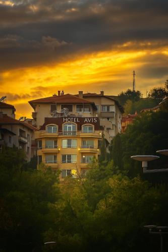 a building with a hotel xvs sign on it at sunset at Hotel Avis in Sandanski