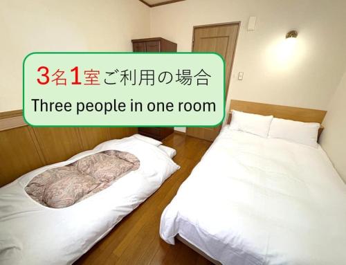 two beds in a room with a sign that reads three people in one room at やすらぎの宿フォーシーズン矢本 in Yamoto