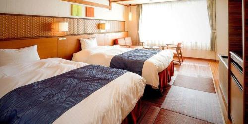 a hotel room with two beds and a window at Kyoto Keburikawa Hotel in Kameoka