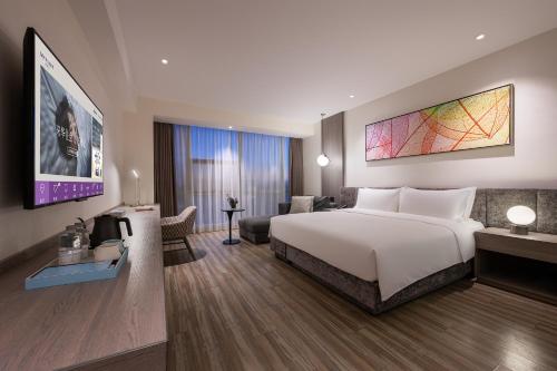 a hotel room with a large bed and a desk at Mercure Shanghai Hongqiao South in Shanghai