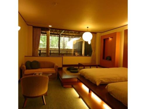 a bedroom with two beds and a couch and a chair at Kyoto Keburikawa Hotel in Kameoka