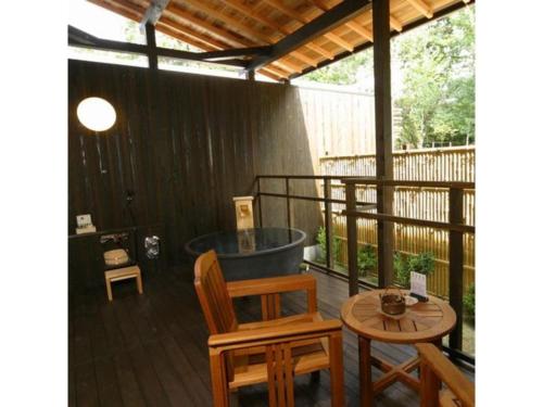 a deck with a tub and a table and chairs at Kyoto Keburikawa Hotel in Kameoka