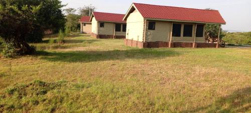 a house with a red roof in a field at Miliki Maasai Mara in Sekenani