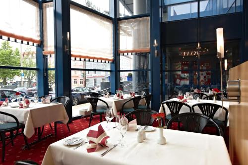 a restaurant with white tables and chairs and windows at IntercityHotel Schwerin in Schwerin
