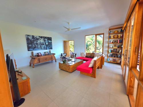 sala de estar con sofá rojo y muebles de madera en ESCAPE to SERENITY SPECTACULAR VIEWS LUXURY VILLA, en Lovina
