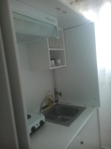a small white kitchen with a sink and a stove at Karagiozos Studios & Apartments in Skopelos Town
