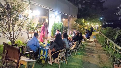 a group of people sitting at a table in a garden at night at Amikaje Farm in Xuan An