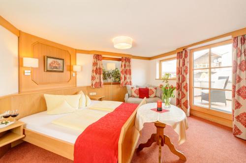a bedroom with a large bed with a red blanket at Familien- und Wellnesshotel "Viktoria" in Oberstdorf
