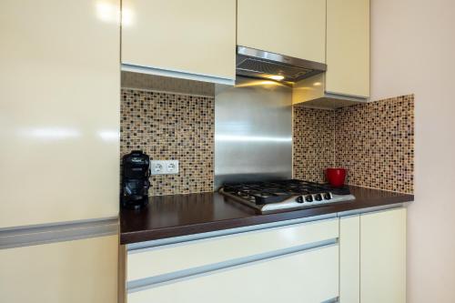 a kitchen with white cabinets and a stove top oven at Borostyán Tó Vendégház in Zalalövő