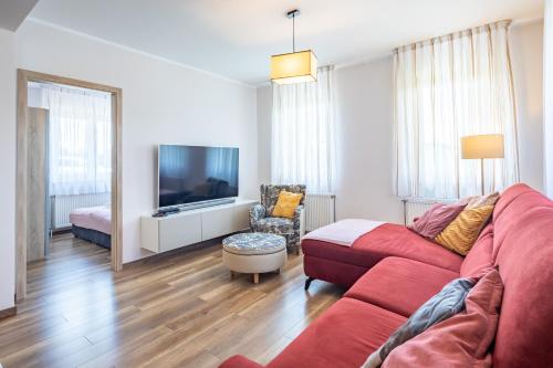 a living room with a red couch and a tv at Borostyán Tó Vendégház in Zalalövő