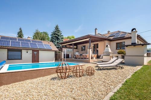 a home with a pool and a house with solar panels at Borostyán Tó Vendégház in Zalalövő