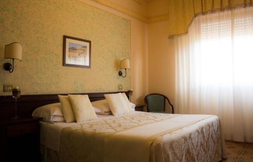 a bedroom with a bed with white sheets and a window at Hotel Ristorante Tre Stelle in Montepulciano