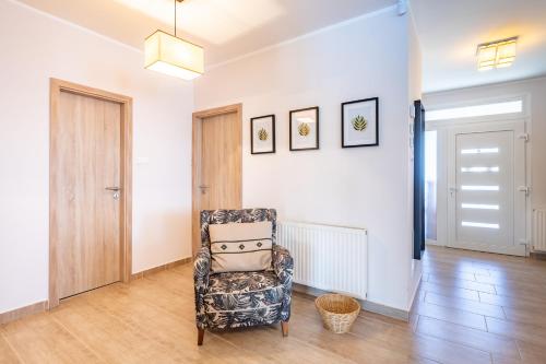 a living room with a chair and a hallway at Borostyán Tó Vendégház in Zalalövő