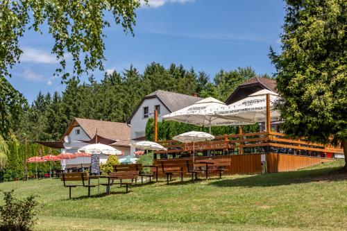 a restaurant with tables and chairs and umbrellas at Borostyán Tó Vendégház in Zalalövő