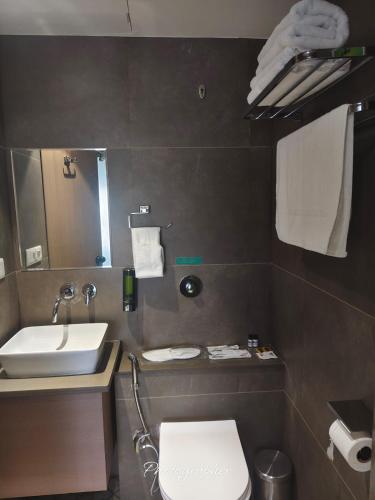 a bathroom with a sink and a toilet and a mirror at Fun Hotels Jamnagar in Jamnagar
