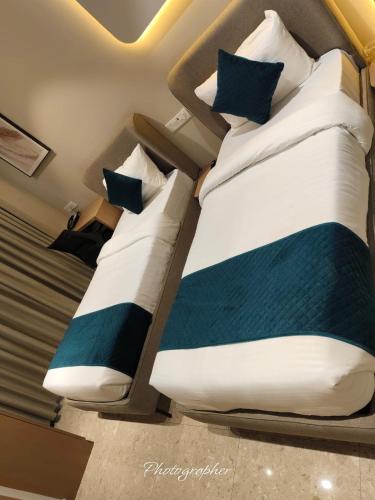 two beds in a small room with blue and white pillows at Fun Hotels Jamnagar in Jamnagar