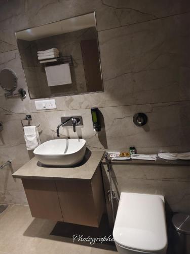 a bathroom with a sink and a toilet and a mirror at Fun Hotels Jamnagar in Jamnagar