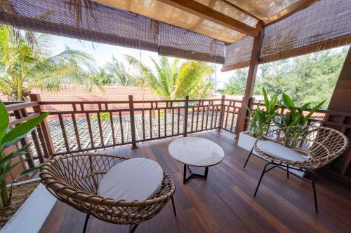 a porch with two chairs and two tables and chairs at Hoianbang Beach Front Villa and Restaurant in An Bang