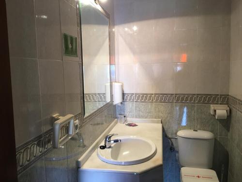 a bathroom with a sink and a toilet and a mirror at La Brisa de Tarik Rooms in Tarifa