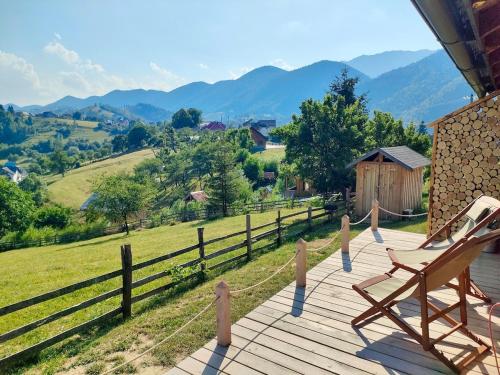 a wooden deck with a chair and a view of mountains at Echo Magura in Măgura