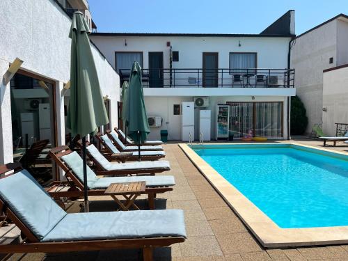 - une piscine avec des chaises longues et des parasols à côté d'un bâtiment dans l'établissement Omega Mamaia Nord, à Mamaia Nord – Năvodari
