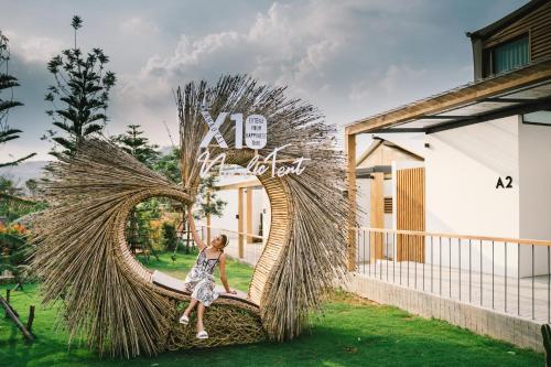 a woman is sitting on a large sculpture in front of a building at The X10 Nordic Tent and Glamping Pool Villa Khaoyai เขาใหญ่ - SHA Certified in Ban Thung Sawang
