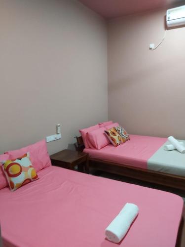 two beds in a room with pink sheets at Araliyaa Tourists Lodge in Daulagala
