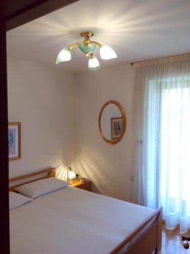 a bedroom with a bed and a mirror and a window at B&B Casa Bazzanella in Cavalese
