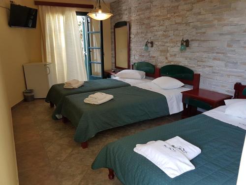 a room with three beds with green and white sheets at Hotel Naxos Beach in Naxos Chora