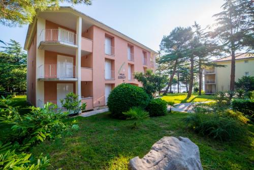 a pink apartment building with a rock in the yard at Belvedere Resort Hotels in Izola