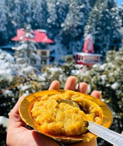 a person holding a piece of food with a knife at Pahadi Zayka Homestay in Chail