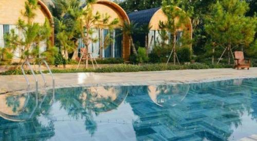 a swimming pool with a house and palm trees at Jun's Home in Buon Ma Thuot