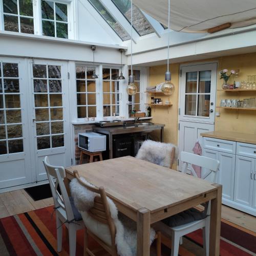 a kitchen with a wooden table and chairs and a kitchen with windows at Eget anneks på landet, tæt på skov og strand in Græsted
