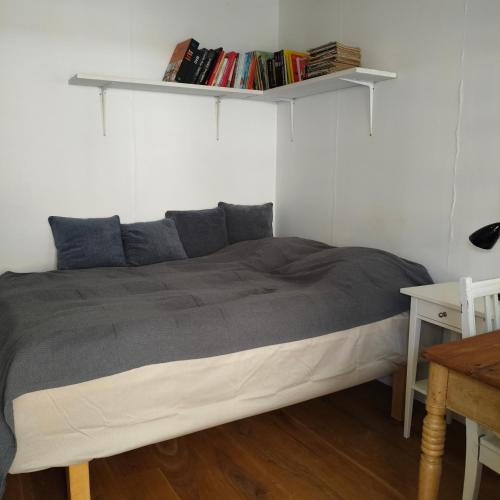 a bedroom with a bed with a shelf on the wall at Eget anneks på landet, tæt på skov og strand in Græsted