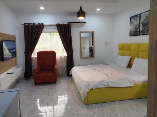 a bedroom with a yellow bed and a red chair at Utako Studio Apartments-City Center in Abuja