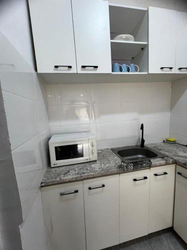 a white kitchen with a microwave and a sink at Utako Studio Apartments-City Center in Abuja